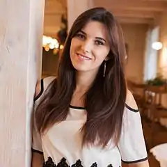 Un portrait manifestement pris sur le vif, impossible de tout contrôler mais les lampes à l'arrière-plan créent des zones claires qui distraient le regard. Le mieux est de les cacher à la prise de vue ; un petit déplacement de quelques cm vers la droite en aurait caché une bonne partie tout simplement derrière la jeune femme.