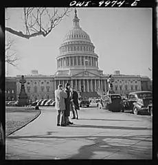 A student on his way from the Library of Congress to the Capitol making notes about what he has seen using a friend's back for a desk
