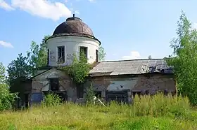Photographie d'une église abandonnée, recouverte partiellement par de la végétation.