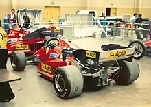 Photographie d'une monoplace rouge, garée dans un stand.