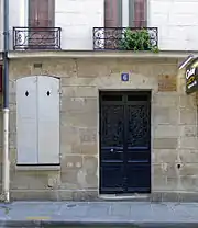 photo d'une façade avec porte d'entrée numérotée 6 et fenêtre aux volets fermés